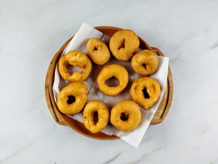 Biscoitos de polvilho fritos sobre um prato forrado com papel-toalha.
