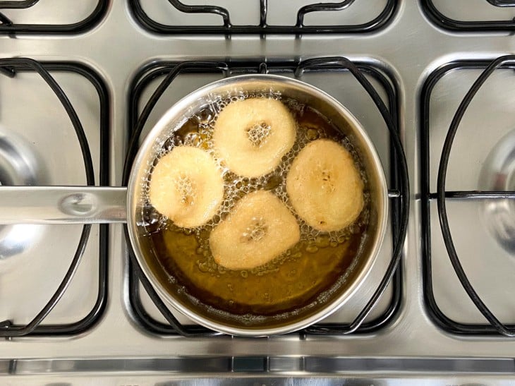 Uma panela com óleo fritando os biscoitos.