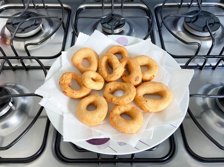 Um recipiente com papel toalha e vários biscoitos de polvilho doce frito.