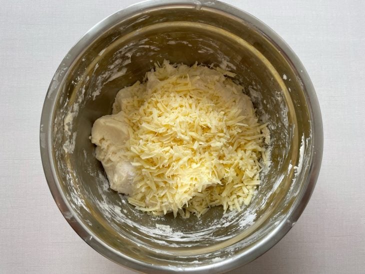 Queijo ralado e sal sendo incorporados à massa.