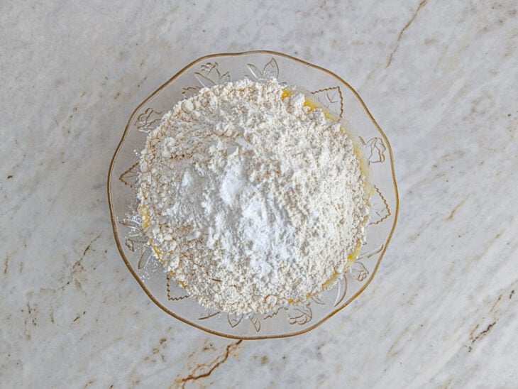 Farinha de trigo, fermento e sal sendo adicionados à mistura líquida.