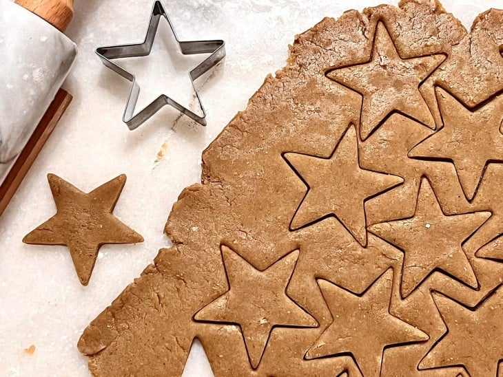 Uma massa de biscoito aberta sendo cortada em formato de estrelas.