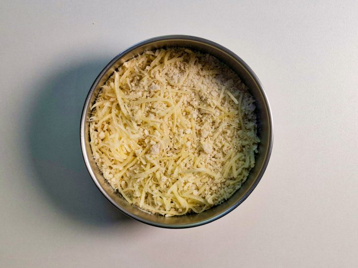 Numa tigela, farinha panko misturada com queijo ralado.
