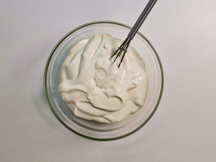 Creme sendo preparado em tigela com cream cheese, creme de leite e açúcar.