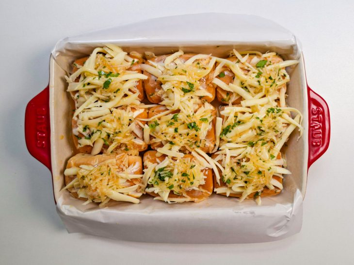 Cobertura com queijo mussarela e pincelada de creme sobre o topo dos pães.
