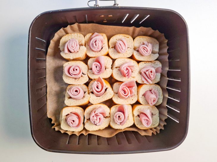 Quadradinhos de presunto dispostos nas bisnaguinhas.