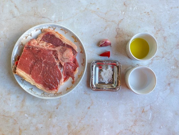 Ingredientes para a receita de bisteca bovina separados em uma bancada.
