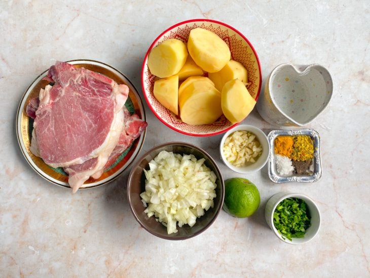 Ingredientes para a receita de bisteca com batatas reunidos em uma bancada.