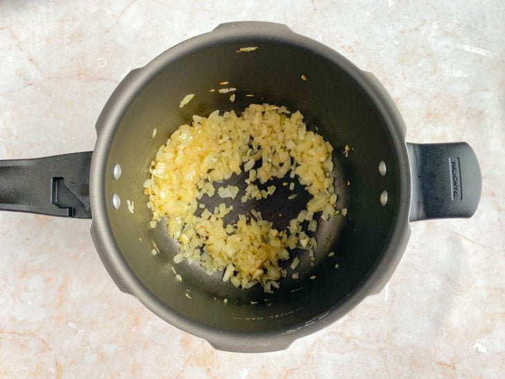 Cebola e alho refogados em uma panela de pressão.