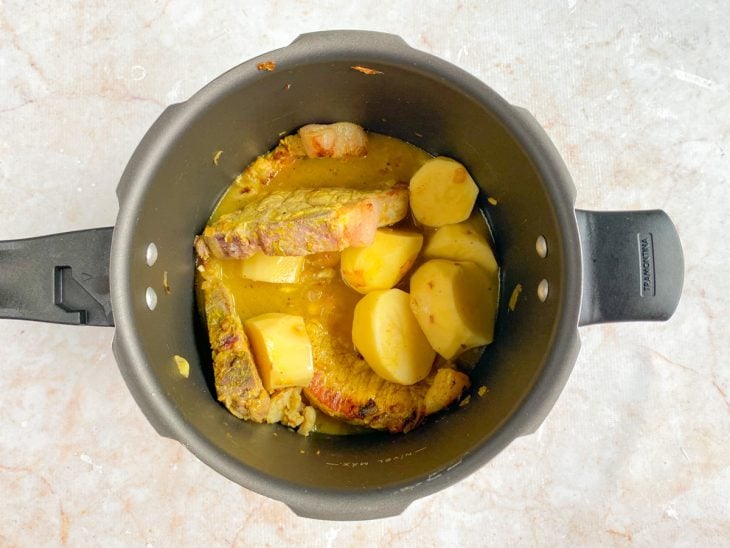 Água, batatas e temperos adicionados na panela.