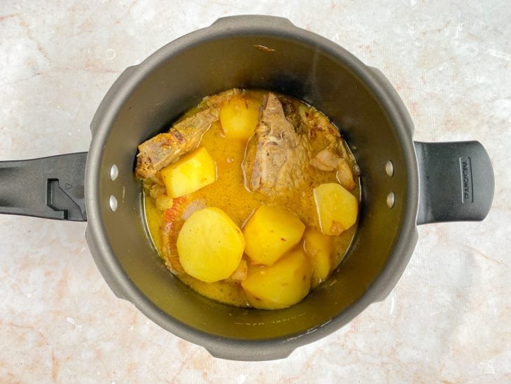 Batatas e bistecas cozidas na panela de pressão.