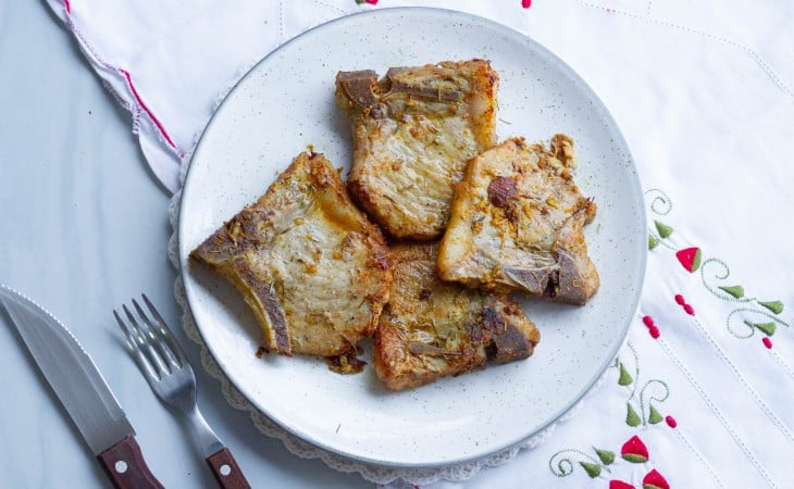 Um prato com 4 bistecas de porco fritas.