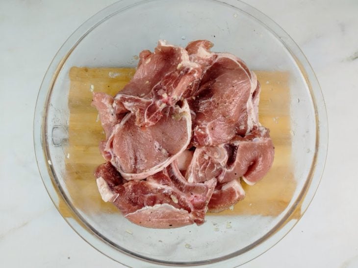 Bistecas temperadas em uma tigela de vidro.