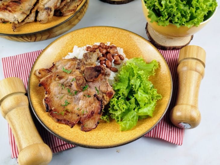 Bisteca grelhada servida com arroz, feijão e salada.