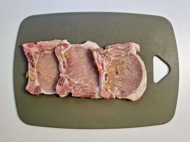 Uma tábua com as bistecas temperadas.