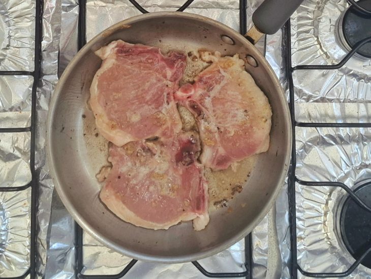 Uma frigideira com as bistecas ao fogo.