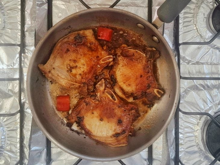 Pimenta e água com as bistecas na frigideira.