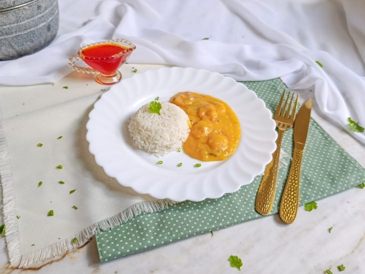 Bobó de camarão com mandioca servido num prato individual acompanhado por arroz branco.