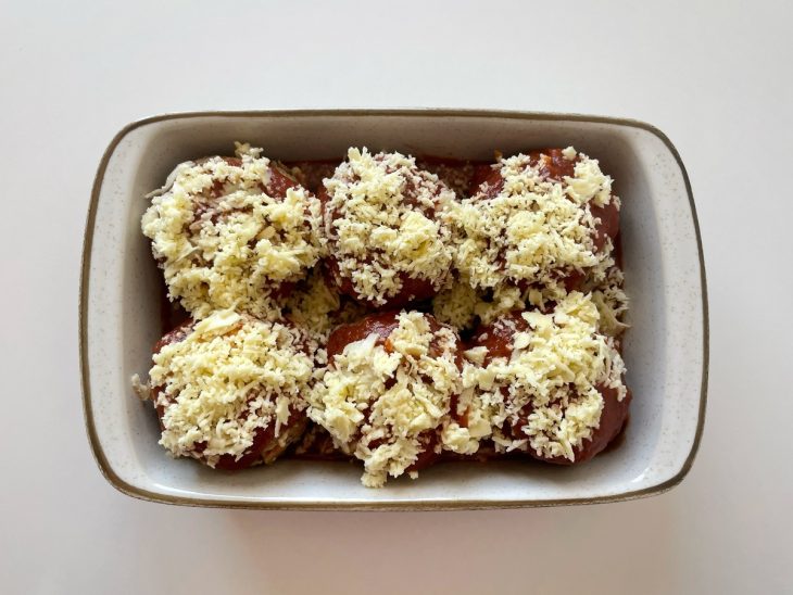 Molho de tomate e mussarela cobrindo as bolas de carne.