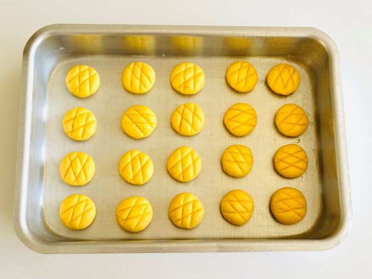 Porções de massa boleadas, achatadas e dispostas em forma.