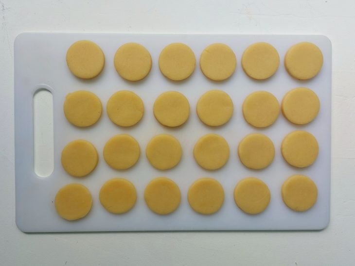Uma tábua com discos da massa para bolinha de queijo.