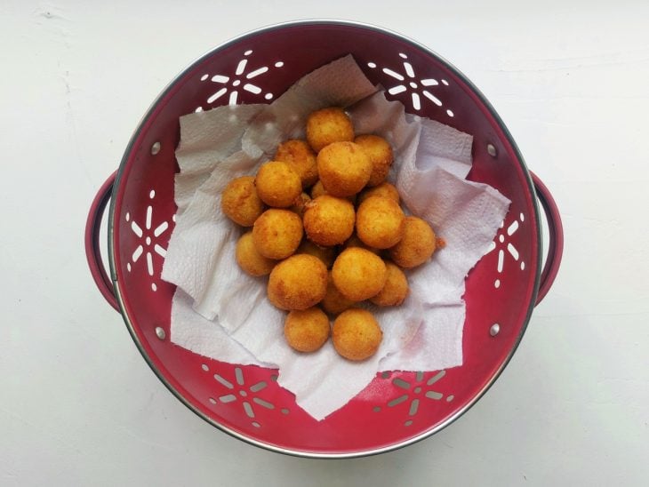 Um recipiente com papel-toalha e bolinhas de queijo após fritura.