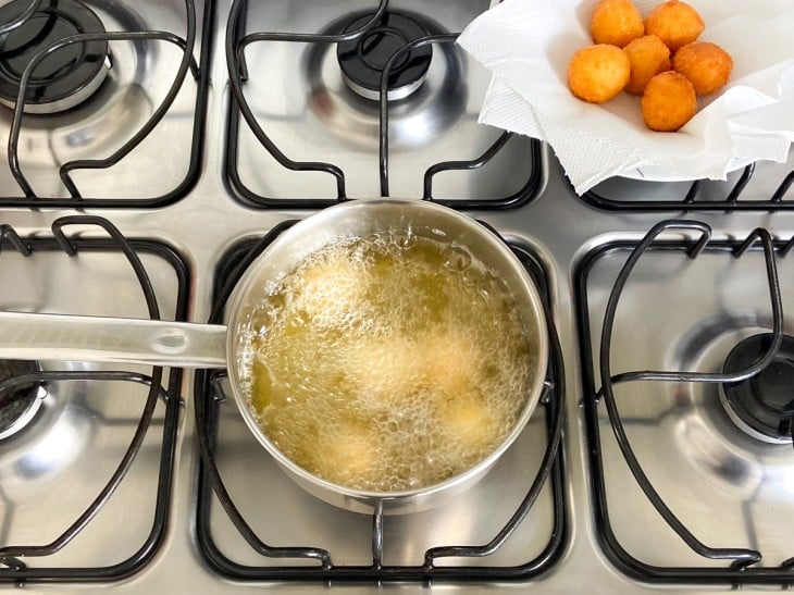 Uma panela com óleo fritando as bolinhas.