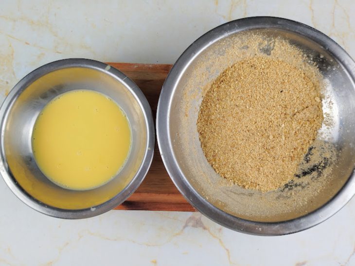Ovo batido em uma frigideira e farinha de rosca em outro recipiente.