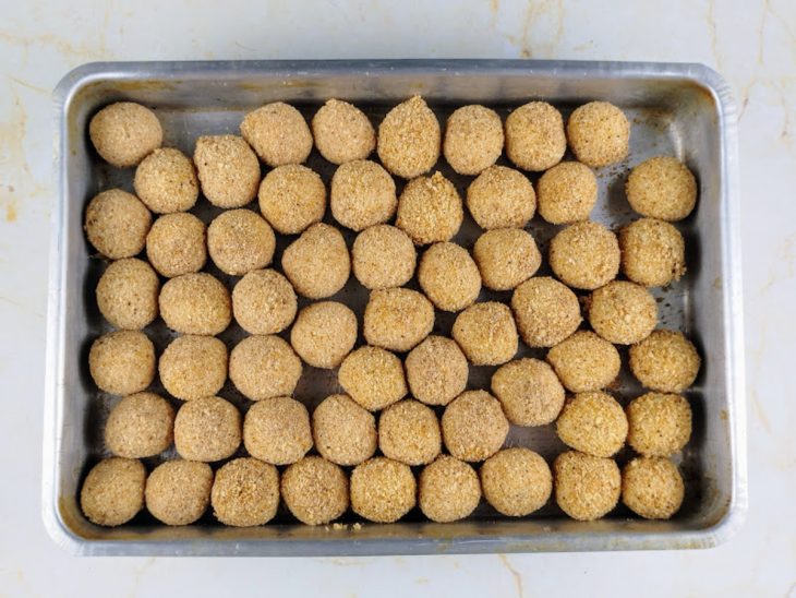 Bolinhas empanadas em uma assadeira.