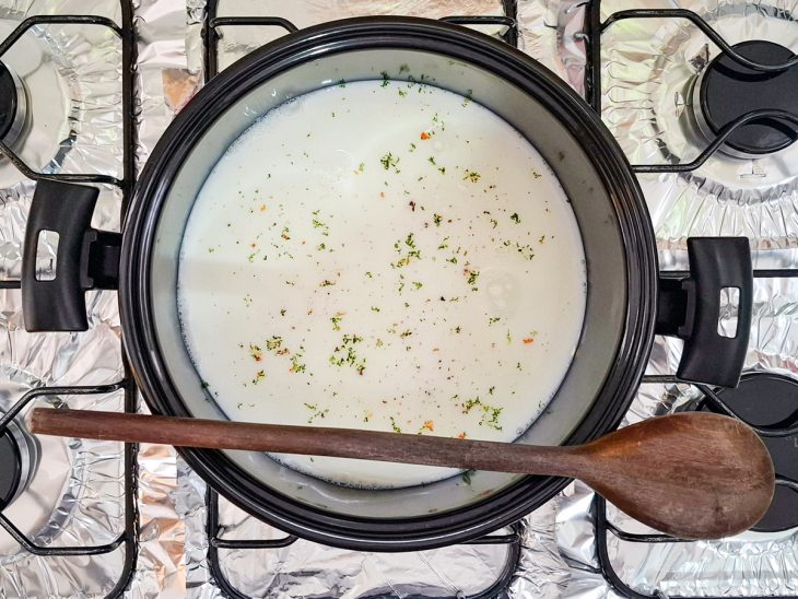 Água, leite, caldo de galinha, sal e margarina misturados em uma panela.