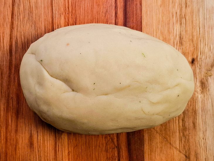 Massa sovada sobre uma tábua de cozinha.