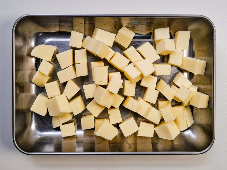 Queijo mussarela picado em cubos em uma forma.