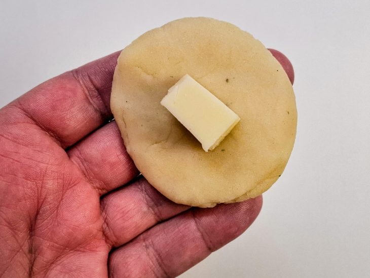 Cubo de queijo sobre a massa achatada.
