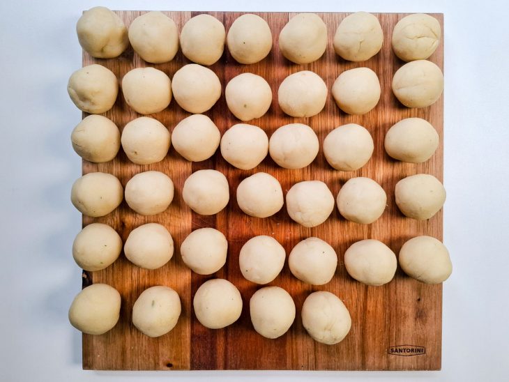 Bolinhas de queijo sobre uma tábua de cozinha.