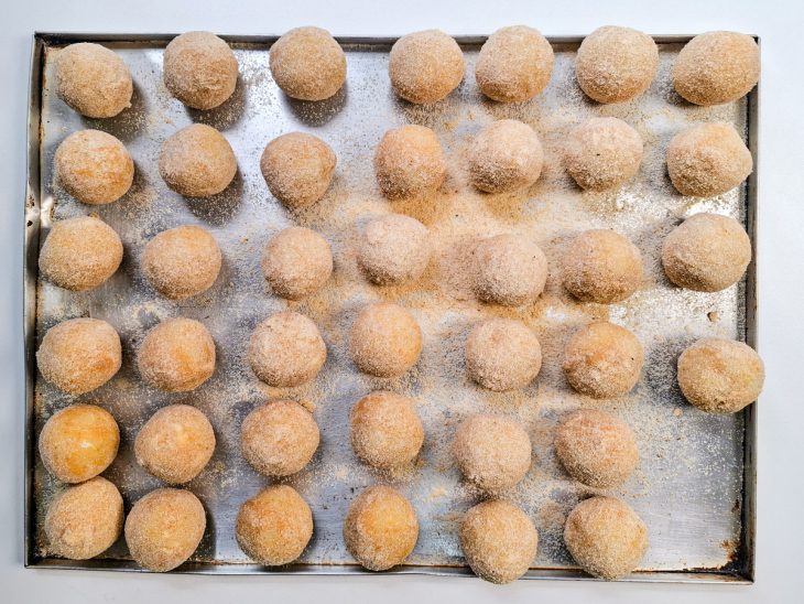 Bolinhas de queijo empanadas sobre uma forma.