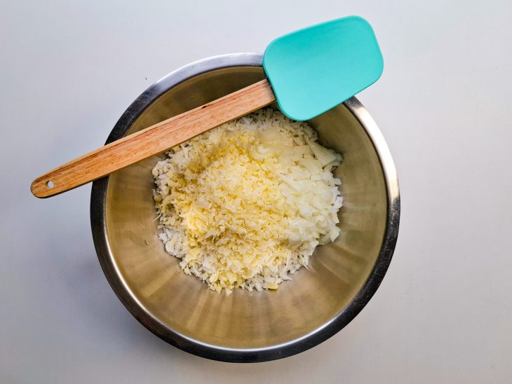 Arroz, cebola e queijo ralado colocados num recipiente.