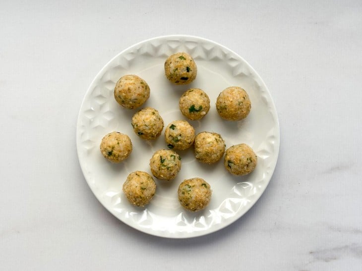 Um prato contendo bolinhos de arroz crus com queijo.