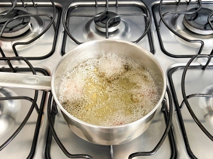 Uma panela com óleo fritando os bolinhos de arroz.