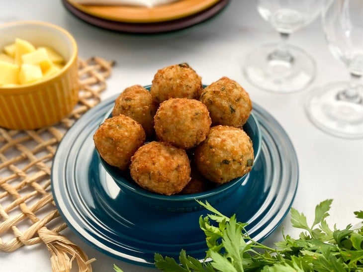 Um recipiente contendo bolinhos de arroz com queijo.