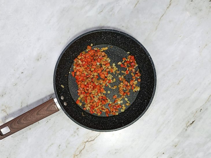 Ingredientes refogados numa frigideira.