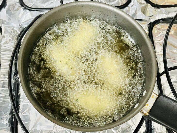 Bolinhos em frigideira com óleo, fritando.