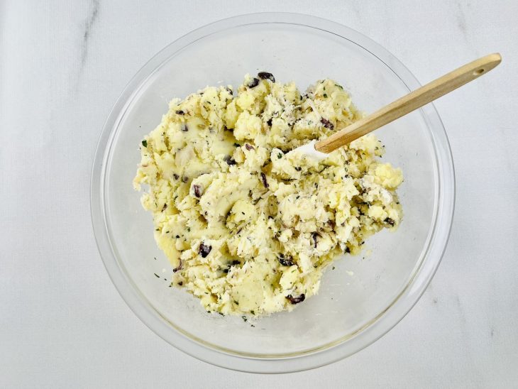 Batata amassada adicionada na tigela com bacalhau e demais ingredientes.