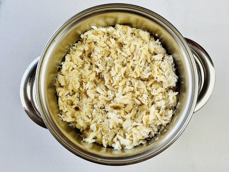 Bacalhau desfiado numa panela.