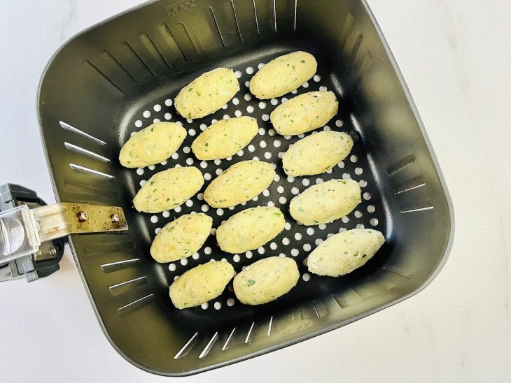 Bolinhos acomodados espaçados no cesto da air fryer.