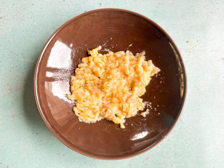 Garfo amassando a banana até obter uma pasta com alguns pedacinhos visíveis.