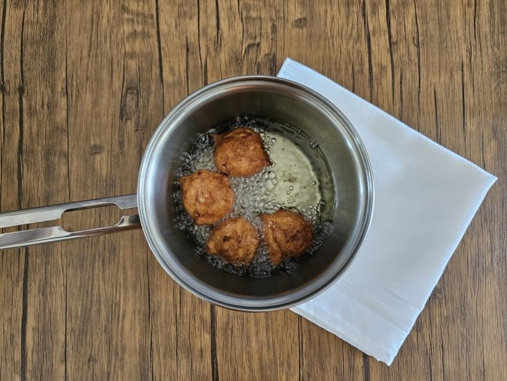 Bolinhos sendo fritos em óleo quente em uma panela.