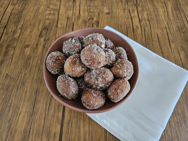 Bolinhos de banana fritos envoltos por açúcar uma mistura branca.