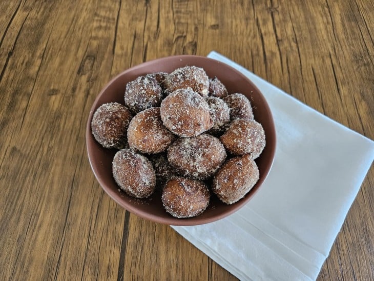 Bolinhos de banana fritos envoltos por açúcar uma mistura branca.