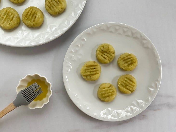 Bolinhas achatadas com um garfo e um pincel no azeite.