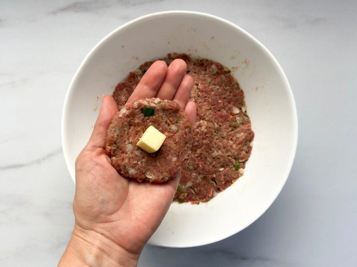 Uma porção da massa de carne moída aberta em formato de disco, recheado com queijo.